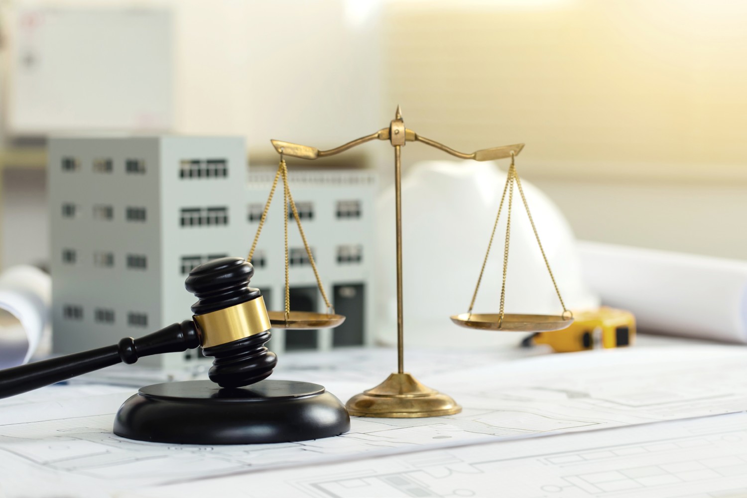 A gavel and balance scales on architectural blueprints, symbolizing justice in construction and legal matters.